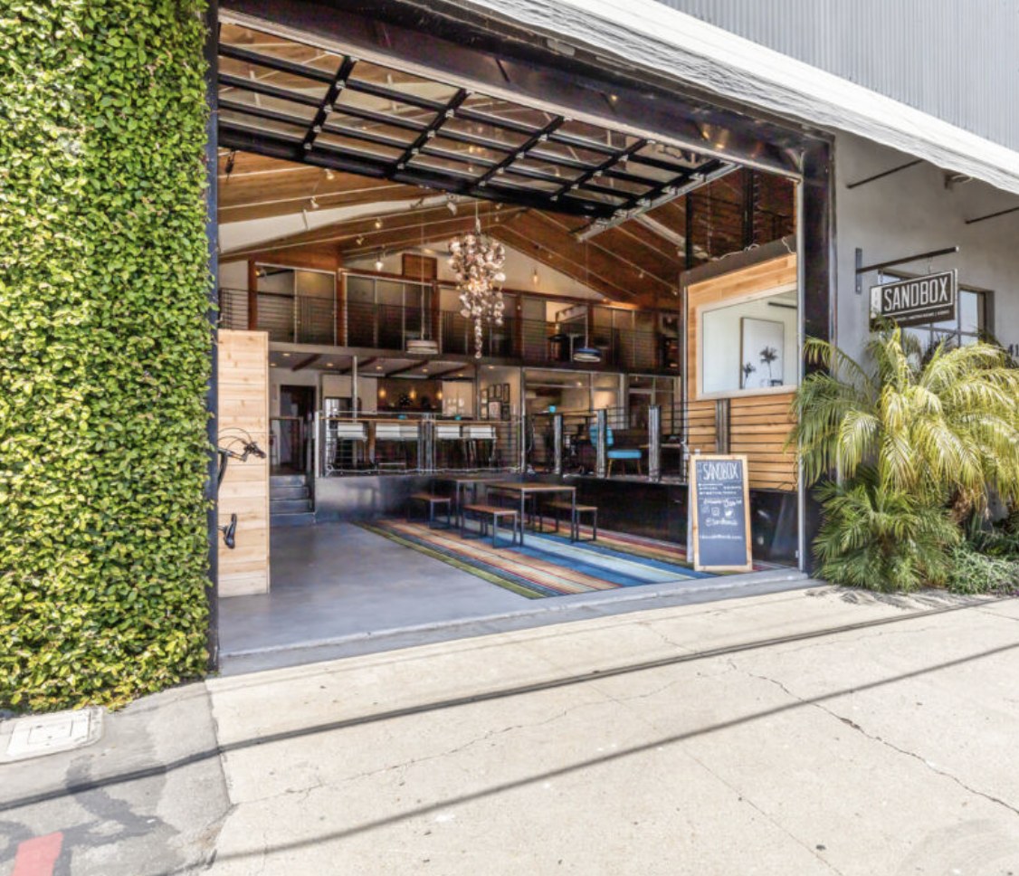 The open garage door entry at Sandbox, with a living wall and a mezzanine workspace inside